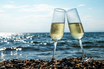 Two glasses of champagne by the sea on the beach. Holiday celebration. Vacation concept.