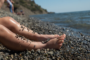 Legs of a small child sitting on the seashore.