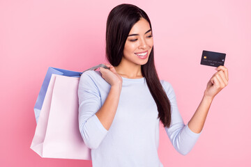 Naklejka premium Portrait of attractive trendy cheerful girl holding bags bank card order delivery decide choose isolated over pink pastel color background