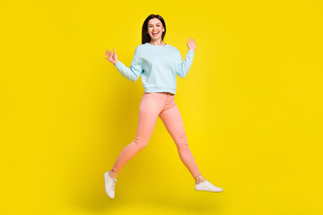 Fototapeta na wymiar Full length body size view of attractive thin cheerful girl having fun jumping isolated over bright yellow color background