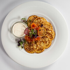 Pancake with smoked salmon and sour cream on a light background, top view. Delicious snack, tapas, brunch