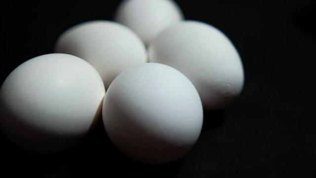 Five fresh white eggs lying down on black surface
