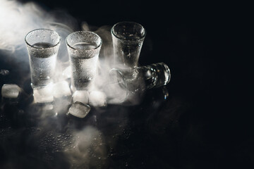 Vodka in shot glasses on dark background.