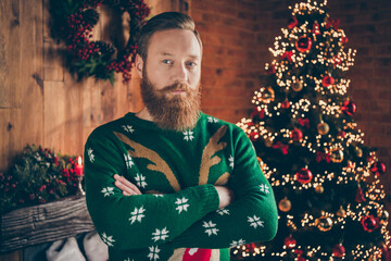 Portrait of attractive serious guy folded arms festal decorated room at modern loft industrial style indoors
