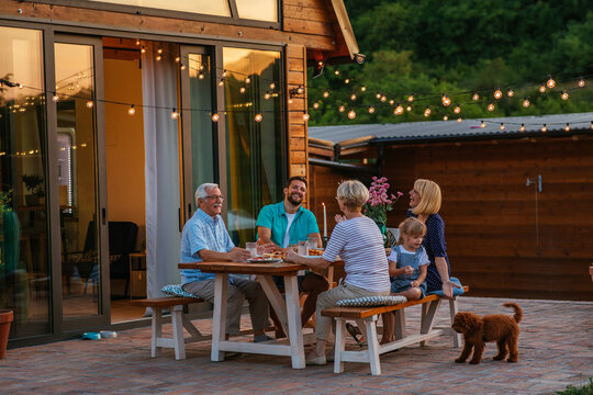 Family Dinner Around Dining Table In The Garden