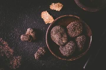 Black truffle in bowl on dark background