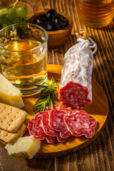 Sliced Salame on Wooden Plate with Cheese and Wine. Italian Appetizer