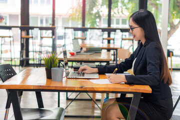 Businesswoman working in a coffee shop with laptop and calculator and notebook. Concept of working in accounting, finance, and investment.