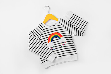 Striped jumper with rainbow on hanger on white background. Cute  kids outfit. Children's clothes...