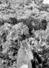 Black and white photo of a young girl from the back, beautiful long blond hair in flight. Walk in nature. In a good mood. Youth and beauty concept. Copy space