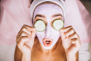 Woman with mask and cucumber on her eyes