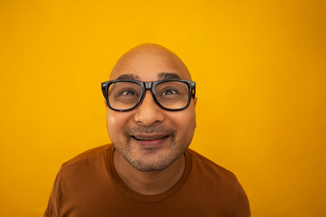 Portrait of a bald man wearing eyeglasses smiling against plain background.