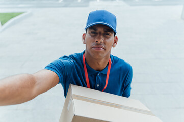 Young delivery man looking at camera while calling intercom to deliver package.