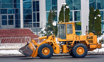 Yellow front loader with scoop for clearing snow. Wheel loader machine ready to removing snow in...