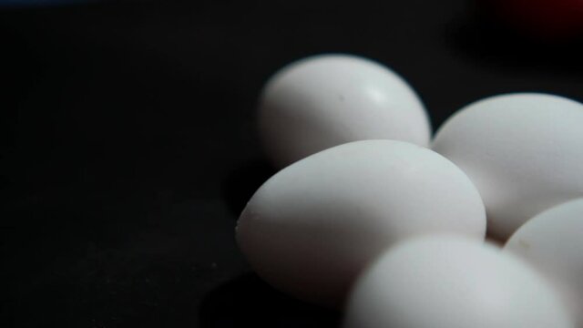 Five fresh white eggs lying down on black surface