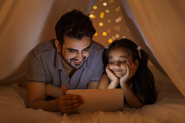 A FATHER AND DAUGHTER ENJOYING USING DIGITAL TABLET TOGETHER