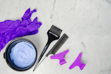 Utencilios decoloración tinte pelo en polvo azul con guantes, peine, pinzas y brocha sobre fondo...