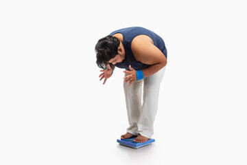 Portrait of a fat man standing on weighing machine and measuring weight with frustration.