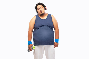 Portait of a fat man standing with headphones around neck exhausted after a workout.