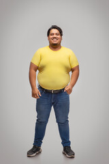Portrait of a fat man standing and smiling against plain background.