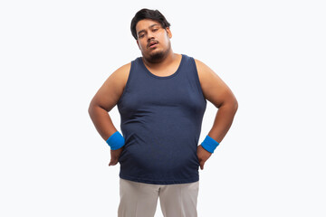 Portait of a fat man standing  exhausted after a workout against plain background.