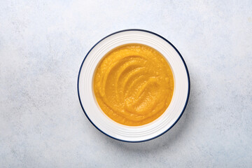 Pumpkin traditional soup with creamy silky texture with sage leaves and red pepper in white plate or bowl. Light grey background. Copy space. Mock up. Top view, flat lay.