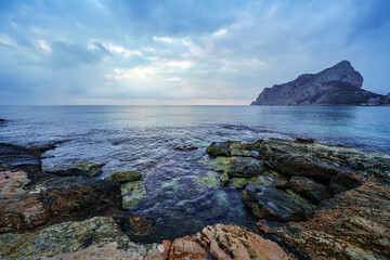 Fototapeta na wymiar Big rocks on the seashore and waves crashing against them.