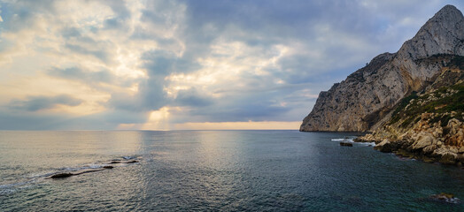 Panoramic seascape with large mountain by the sea and golden sunset.