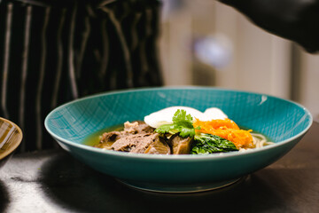 Beef ramen soup with poached egg and vegetables at a restaurant