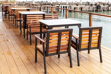 Empty brown wooden dining table set at seaside terrace