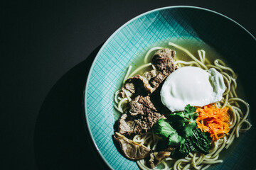 Beef ramen soup with poached egg and vegetables at a restaurant