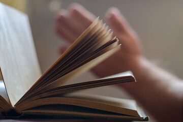 Defocused shot of an old open book and two men's hands. Palms fo