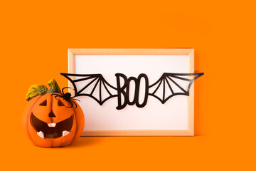 Happy halloween holiday concept. Jack o lantern, handmade paper decorations, boo text with bat wings in frame on orange background. Halloween festival party, greeting card with copy space.