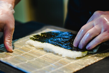Fototapeta na wymiar Sushi chef making maki and sashimi sushi at a sushi restaurant
