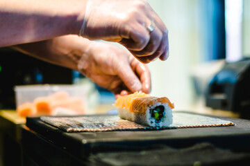 Sushi chef making maki and sashimi sushi at a sushi restaurant