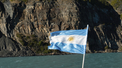 View of a waving flag of Argentina on the background of sea and rocks