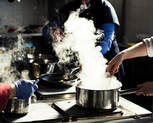 Chef cooking soup and water evaporating from a pot at a restaurant kitchen