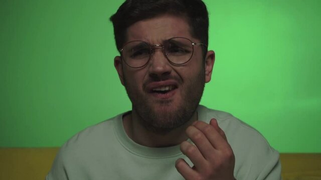 man feeling disgusted and grimacing while eating tasteless popcorn on green