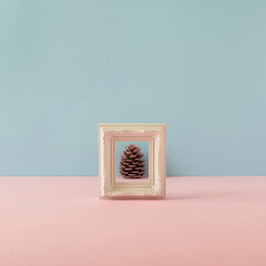 Holiday composition made of white frame with pinecone on pastel background.. MInimal winter, Christmas or New Year concept. Copy space.