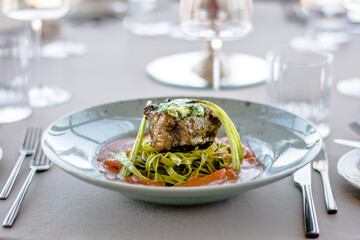 Grilled and flamed ox steak with green herb noodles in a tomato puree at a restaurant