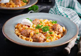 Italian traditional ditalini pasta with meatballs in tomato sauce and vegetables in bowl.  Ditalini pasta and beef balls  with marinara tomato sauce.