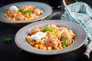 Italian traditional ditalini pasta with meatballs in tomato sauce and vegetables in bowl.  Ditalini pasta and beef balls  with marinara tomato sauce.