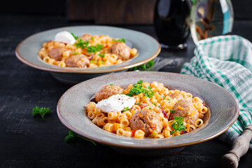 Italian traditional ditalini pasta with meatballs in tomato sauce and vegetables in bowl.  Ditalini pasta and beef balls  with marinara tomato sauce.
