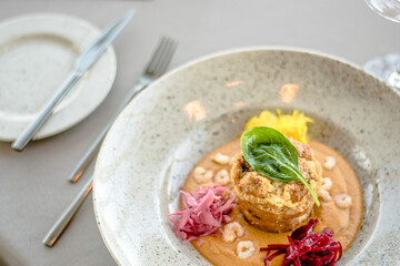 Pike cutlet with pumpkin sauce and fermented cabbage in different colors at a restaurant