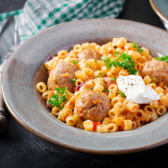 Italian traditional ditalini pasta with meatballs in tomato sauce and vegetables in bowl.  Ditalini pasta and beef balls  with marinara tomato sauce.