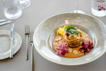 Pike cutlet with pumpkin sauce and fermented cabbage in different colors at a restaurant