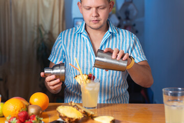 a bartender at a house party pouring a cocktail from a shaker with fresh oranges and alcohol