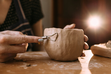 Woman's hands with homemade handmade clay or ceramic pot. The clay master sculpts the product in the kitchen. Home creativity © Andrii Lysenko
