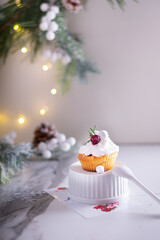 Christmas cupcakes with vanilla frosting, cranberries and rosemary on white background. Vertical