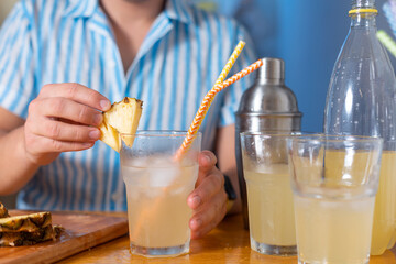 Man decorate the cocktail with a pineapple wedge at home for party